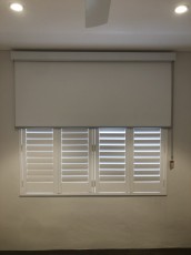 Varas Blockout White in a White Square Faced Top Cassette over a plantation shutter not our shutter